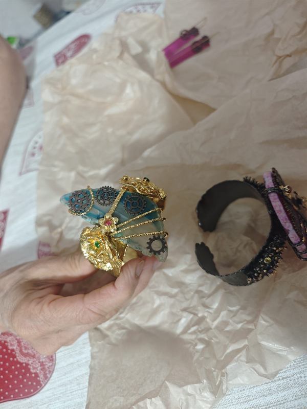 Due bracciali gioiello, uno dorato e uno nero, decorati con pietre e ingranaggi